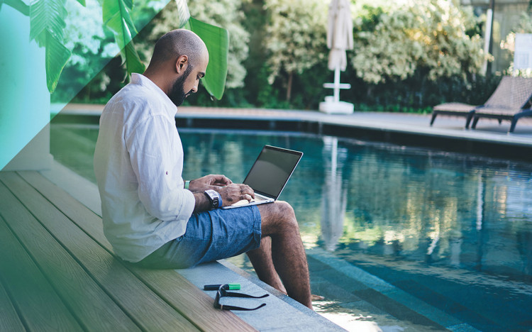 Image d'un homme sur son ordinateur les pieds dans l'eau de sa piscine