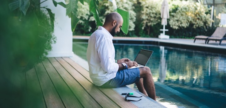 homme avec pc les pieds dans leau de sa piscine