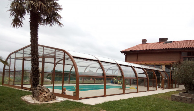 Abri piscine haut Abrisol adossé à une maison coloris marron