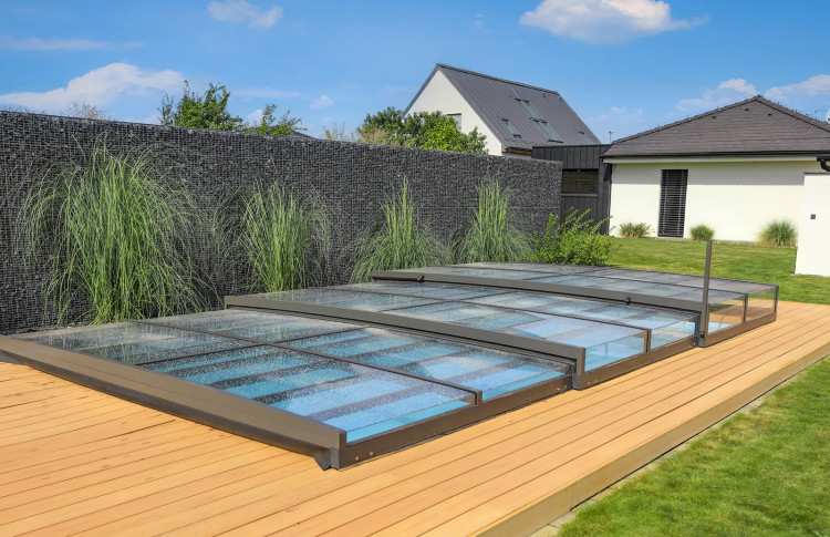 Abri piscine ultra bas ALUKOV au design minimaliste Abri piscine ultra bas télescopique ALUKOV fermé sur un bassin résidentiel avec un impact visuel minimal dans le jardin